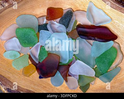 A collection of multi-colored sea glass is arranged in a wood bowl Stock Photo