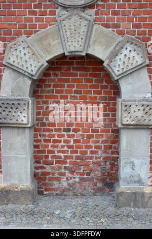 Old bricked up stone arch set in a red brick wall creating a textured architectural background with historic character and symmetry. Stock Photo