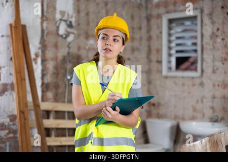 Female architect taking notes in building under renovation Stock Photo