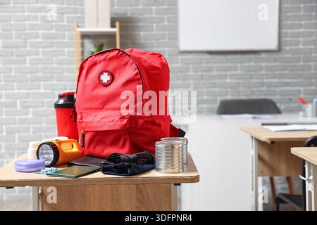 Emergency backpack with necessities on desk in classroom Stock Photo