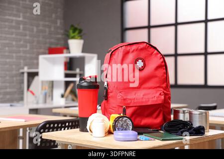 Emergency backpack with necessities on desk in classroom Stock Photo