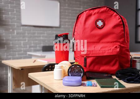 Emergency backpack with necessities on desk in classroom Stock Photo
