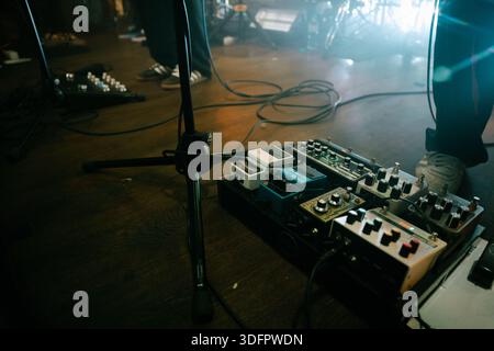 Guitar effects pedalboard on stage floor with cables and microphone stand Stock Photo