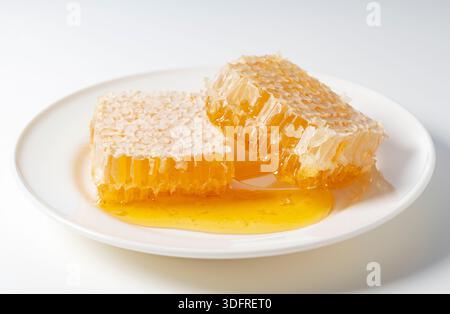 Fresh Honeycomb with Dripping Raw Honey on White Plate Isolated on White Background Stock Photo