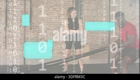 Observing woman in black supervising man in red doing battle ropes at gym with UI overlay Stock Photo