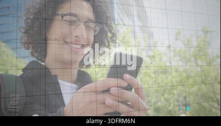 Smiling man wearing dark jacket, glasses holding smartphone, viewing grid overlay near campus trees Stock Photo