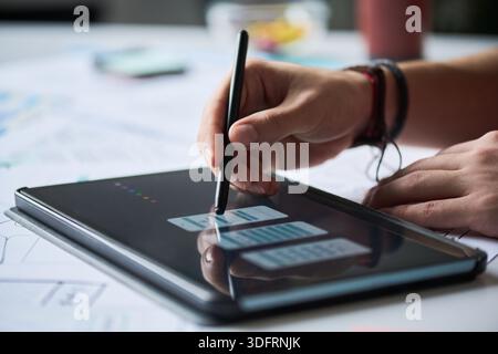 Close-up of unknown man using stylus to design user interface on digital tablet, hand drawing wireframe layout for mobile application, working on technology project Stock Photo