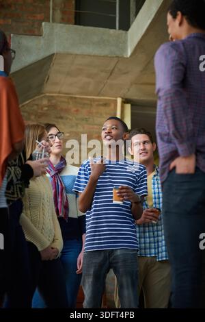 Talking, low angle and people on campus at university for conversation, hangout and socializing. College, students and men and women in lobby chatting Stock Photo
