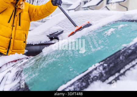Removing snow from car windshield. Clean car window in winter from snow. Stock Photo