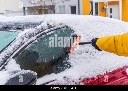 Removing snow from car windshield. Clean car window in winter from snow. Stock Photo