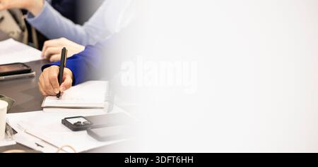 Person's hand writing in a spiral notebook, capturing information during a professional meeting Stock Photo