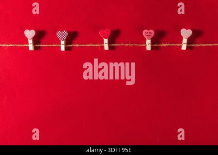 Decorative hearts hanging on a string against a red background for a celebration Stock Photo