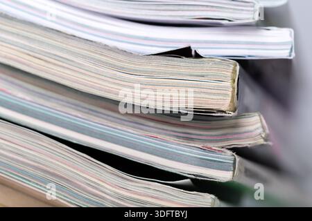 Stacked magazines showing different cover designs and colors on a plain background Stock Photo