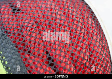 Close up texture of red synthetic mesh fabric on sport shoe displaying intricate perforated pattern and vibrant sporty style conveying dynamic energy Stock Photo
