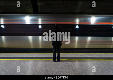 Lonely man standing on platform watching train passing by in subway or train station. a lonely businessman in suit standing on train platform Stock Photo