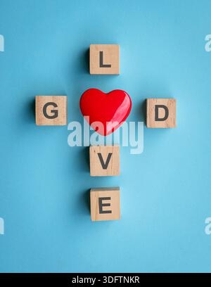 Text on wood blocks with red heart shape, on blue background. God is love concept. Stock Photo