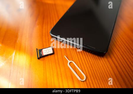 Sim Card and Eject Pin next to smartphone. nano sim card on desk, close-up Stock Photo