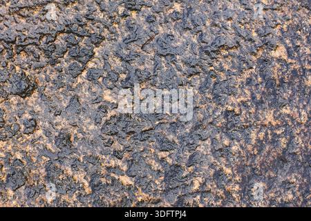 Rough dark texture of rusty uneven metal surface with granular pattern feeling weathered and gritty showing abstract decay and solid strength of aged Stock Photo