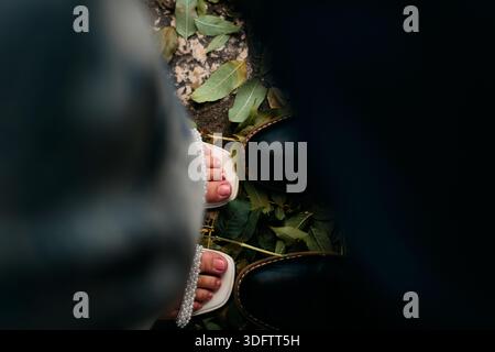 Top Down View of a Couples Feet Standing on Fallen Leaves. Romantic Meeting Concept Stock Photo