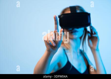 Young woman experiencing virtual reality and interacting with digital interface, common VR technology concept Stock Photo