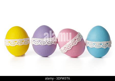 Colorful eggs sit in a row decorated with lace on a white background Stock Photo