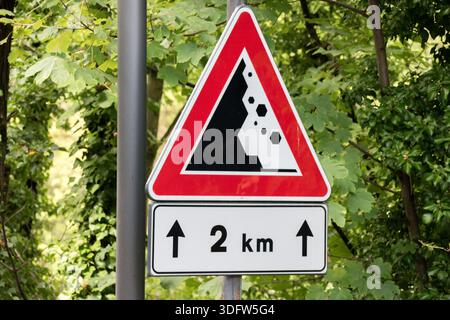 The rockfall road sign warns drivers of road sections where there is a risk of rocks or stones falling from slopes onto the roadway. Stock Photo