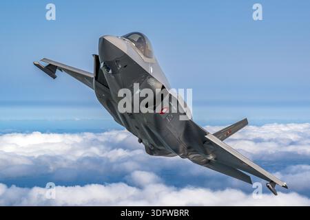The Royal Danish Air Force showcases the F-35A Lightning II, a stealth multirole fighter with single-seat and single-engine configuration powered by the Pratt & Whitney F135 turbofan. This close-up air-to-air image shows the pilot in the cockpit during Danish Airpower 2025, highlighting the aircraft’s advanced avionics, supersonic capability, stealth design, and tactical maneuverability. The F-35A demonstrates Denmark’s operational readiness and modern aerial defense technology. Stock Photo