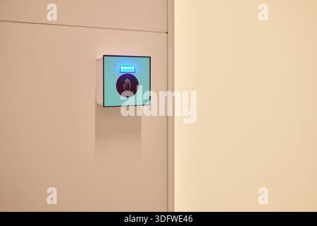 This is a modern smart touch sensor device installed on a wall, featuring a blue LED indicator Stock Photo