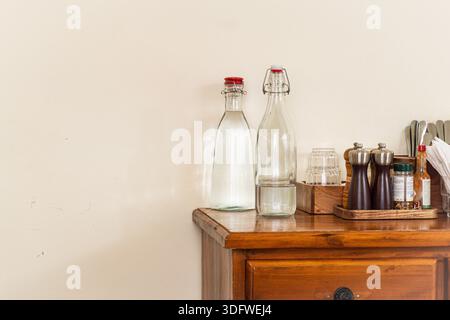 Wooden dresser with two bottles of water and two salt and pepper shakers on top. The bottles of water are clear and the shakers are silver Stock Photo