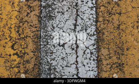 Vertical yellow and white stripe of painted asphalt with cracked rough texture, fragment of marked pedestrian crossing on road or highway in two color Stock Photo