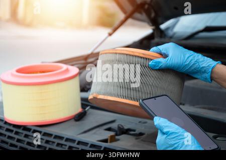The mechanic is inspecting the old engine air filter. Stock Photo