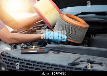 The mechanic is inspecting the old engine air filter. Stock Photo