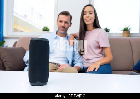 Couple using smart speaker, smart home system appliance, modern assistant || Model released Stock Photo