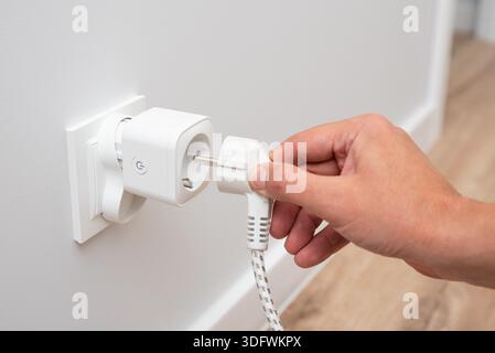 Using Wi-fi smart socket on the wall in a smart home, controlling electricity consumption Stock Photo
