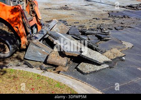 Heavy machinery is lifting removing broken asphalt pieces from construction site Stock Photo