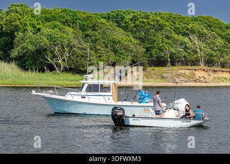 two motor boats passing each other with the people onboard talking. Stock Photo