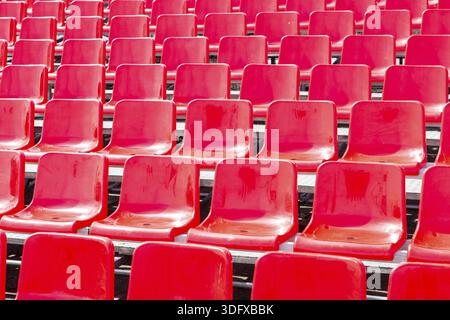 Rows empty bright red plastic seats in a stadium Stock Photo