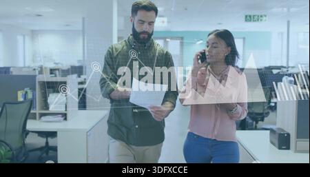 Walking two coworkers in business attire in office talking paper phone and tablet with data charts Stock Photo