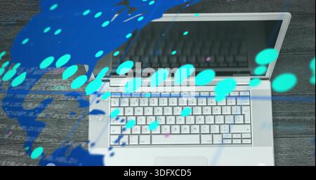Displaying silver laptop on dark wooden desk, showing keyboard, trackpad, cyan map, code overlays Stock Photo