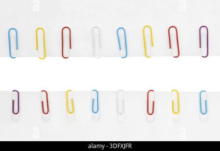 Collection of colored paper clips on a white paper background Stock Photo