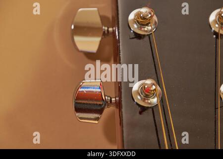 Close-up of tuning pegs and strings of an acoustic guitar on a beige background with copy space Stock Photo