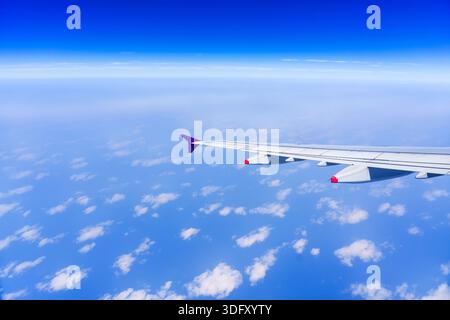The view from the airplane window to the clouds and sunset. Airplane wing above thick light blue gradient sky. Wonderful breathtaking view Stock Photo