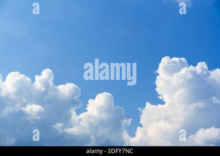 White fluffy cumulus clouds in clear blue sky on sunny day Stock Photo