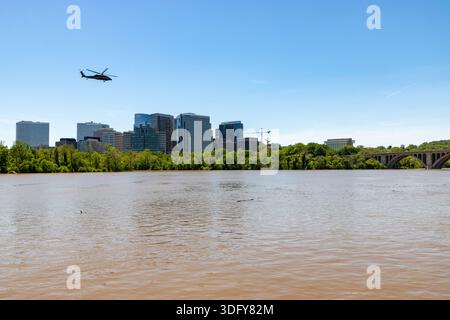 A helicopter flies over the murky Potomac River and Rosslyn skyline near Key Bridge after heavy rains in Washington, DC and Arlington, VA Stock Photo