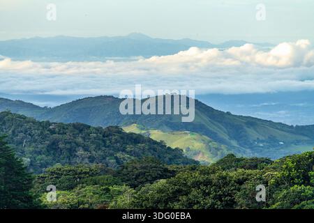 View west from Monteverde resort at sunrise over the hills towards Pacific ocean with sun breaking through clouds Stock Photo