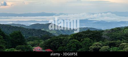 View west from Monteverde resort at sunrise over the hills towards Pacific ocean in broad panoramic format Stock Photo