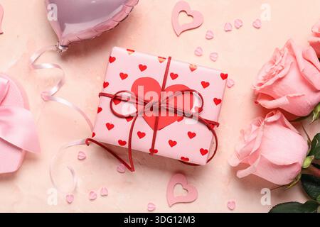 Gift boxes with air balloon, decorative hearts and rose flowers on beige background. Valentines Day celebration Stock Photo