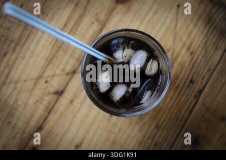Soda glass whit ice cubes and straw on wooden table Stock Photo