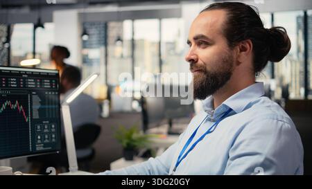 Close up of happy day trader analyzes stock market price candlestick charts, making buy and sell decisions in office. Cheerful stockbroker places client orders using trading platform Stock Photo