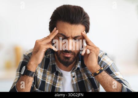 Closeup portrait of tired arab man suffering from headache Stock Photo